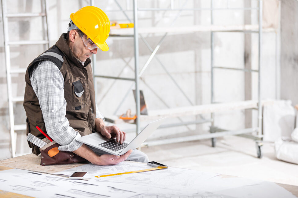 Ein Handwerker mit Laptop auf der Baustelle