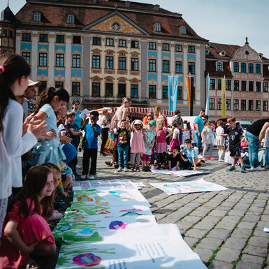 Eine Gruppe von Kindern steht zusammen rund um selbstgestaltete Plakate zum Thema Toleranz