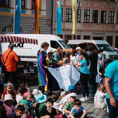 Eine Gruppe von Kindern steht oder sitzen zusammen rund um selbstgestaltete Plakate zum Thema Toleranz