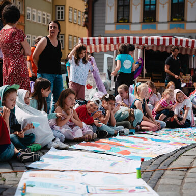 Kinder sitzen auf dem Boden rund um selbstgestaltete Plakate zum Thema Toleranz