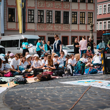 Kinder sitzen auf dem Boden rund um selbstgestaltete Plakate zum Thema Toleranz