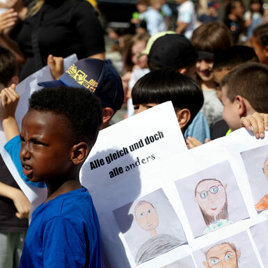 Kinder halten selbstgemalte Plakate zum Thema Toleranz