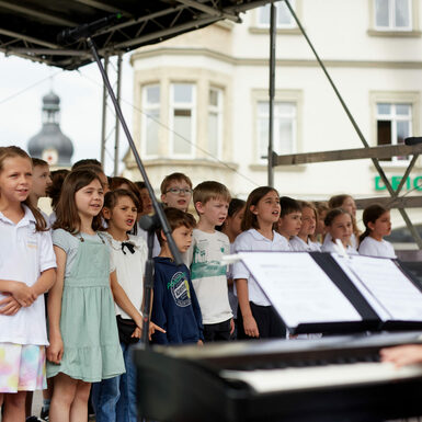 Eine Gruppe von Kindern steht auf der Bühne und singt ein Lied.