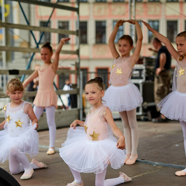 Eine Gruppe von Kindern in Ballettkleidung steht auf der Bühne und tanzt.