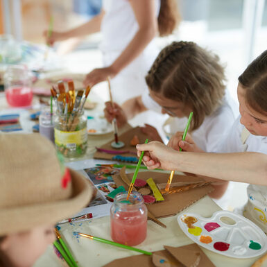 Kinder malen mit Pinsel und Farbe.