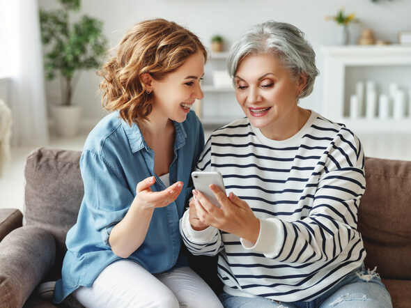 Jugendliche hilft älterer Frau am Smartphone
